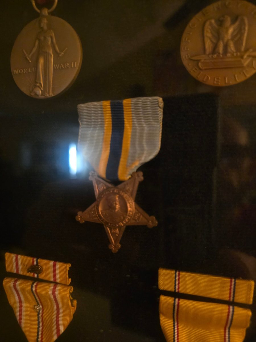 His medals as mounted and kept by the family: the World War II Victory Medal (top left) and the reverse of the Good Conduct Medal (top right, &ldquo;Efficiency, Honor, Fidelity&rdquo;), a five-pointed star service medal, and two ribbon bars.