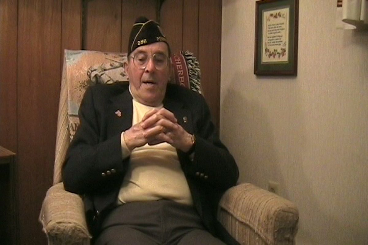 Allen, at home in 2006, hands folded, mid-story.