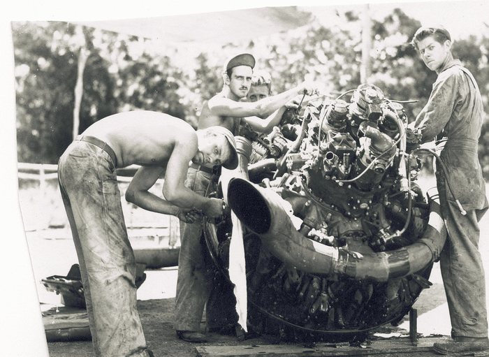 Ground crew work on an exposed aircraft engine.