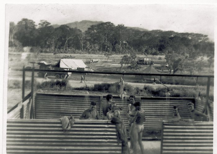 The camp's open-air shower -- a makeshift stand rigged for the men on the slope, with servicemen gathered round it.