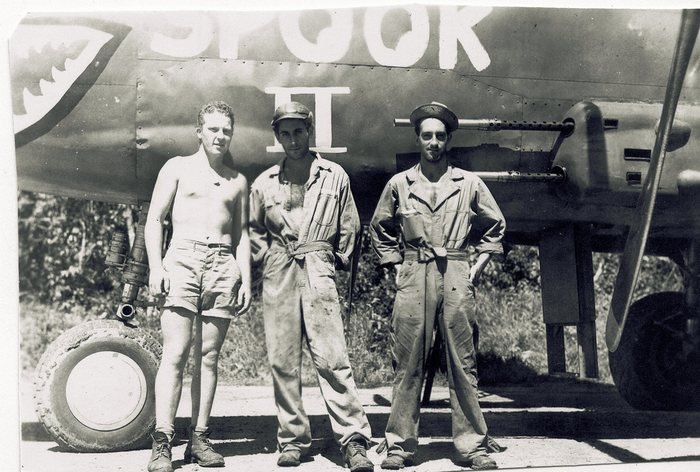 Three crewmen, one shirtless, beneath “Spook II.”