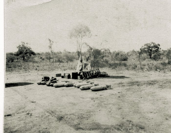 Bombs laid out on the ground beside wooden crates.