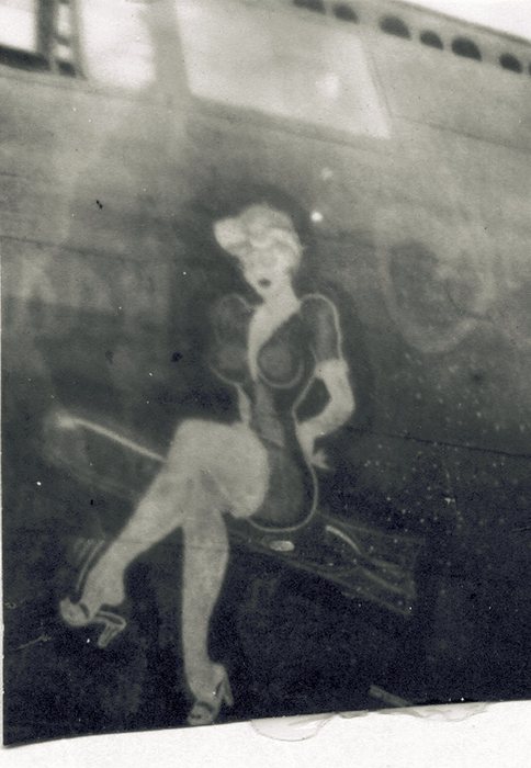 Pin-up nose art — a woman seated on a bomb, painted on the fuselage.