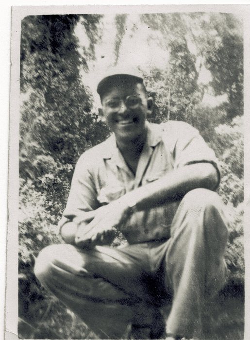 Allen, wearing glasses, seated under the trees.