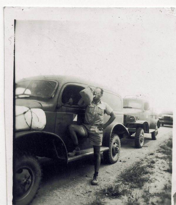 A truck convoy loaded with servicemen — that's Allen taking a big swig from a large water jug.