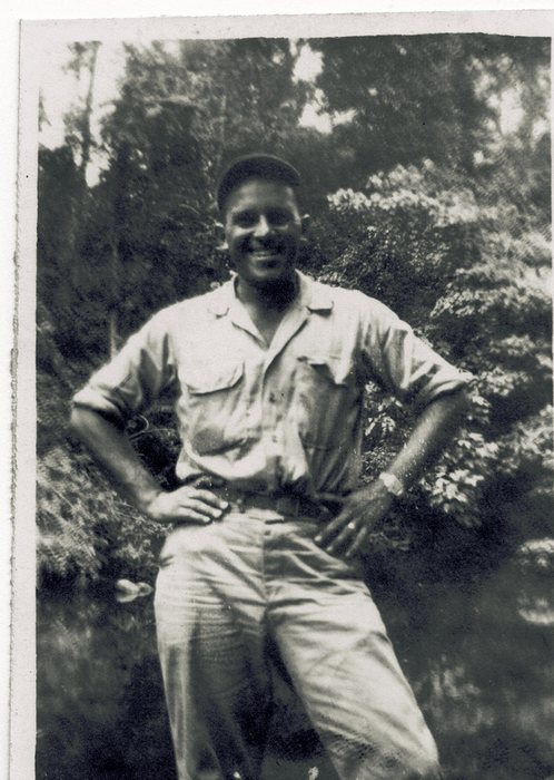 Allen, hands on hips, in front of the jungle tree line.