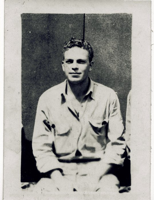 A seated serviceman with wavy dark hair.