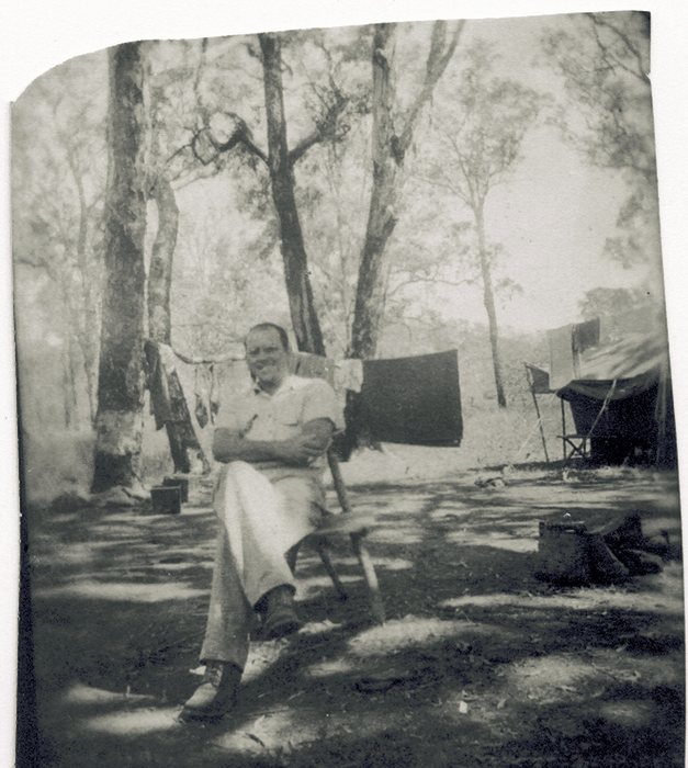 Allen relaxes in a folding camp chair, laundry on the line behind him.