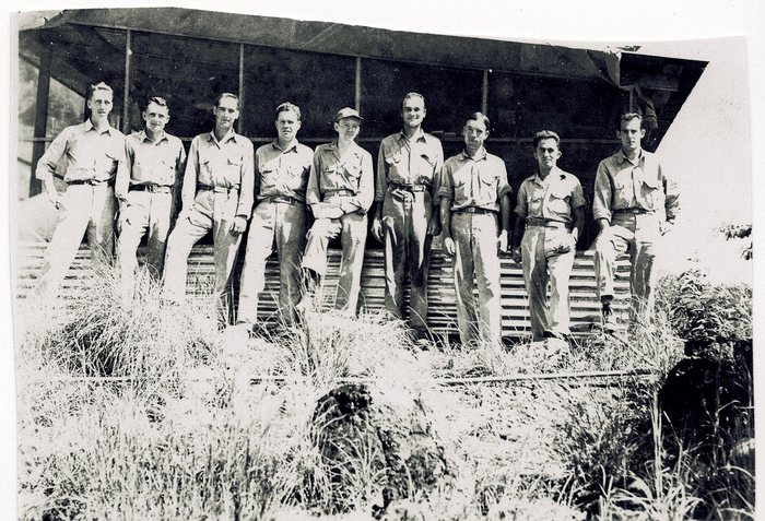 The squadron, more than a dozen men, lined up in two ranks before a camp building.