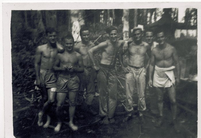 A group of servicemen, freshly washed up, one wrapped in a towel.
