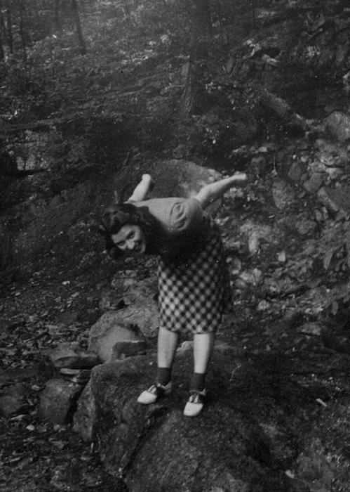 Catherine poses playfully on a boulder in the woods, the same outing.