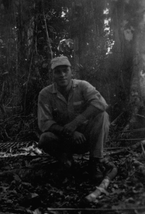 Allen sitting in the jungle in fatigues and cap.