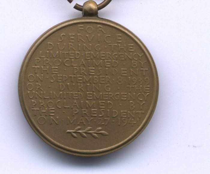 The reverse of a bronze service medal, its raised lettering reading "FOR SERVICE DURING THE LIMITED EMERGENCY PROCLAIMED BY THE PRESIDENT ON SEPTEMBER 8 1939 OR DURING THE UNLIMITED EMERGENCY PROCLAIMED BY THE PRESIDENT ON MAY 27 1941", with a small laurel spray struck beneath the last line. The suspension ring shows at the top edge of the frame.
