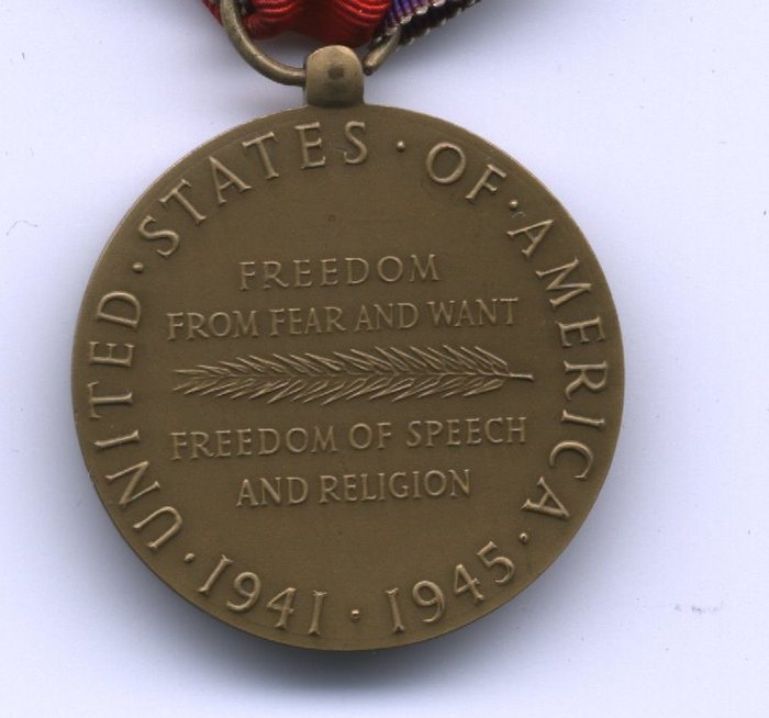 The reverse of a bronze medal: "UNITED . STATES . OF . AMERICA" arcs around the rim with the dates ". 1941 . 1945 ." completing the circle along the bottom. In the centre, "FREEDOM FROM FEAR AND WANT" is lettered above a laurel spray and "FREEDOM OF SPEECH AND RELIGION" below it. The broad red centre of the ribbon, with one rainbow-striped edge, is folded through the suspension ring at the top.