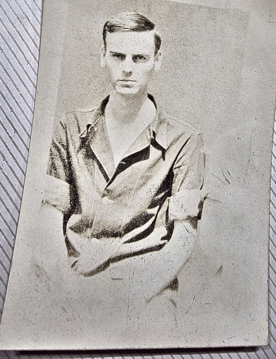 Waist-up portrait of a young man in a light open-collar shirt with the sleeves turned back, arms folded across his chest, looking straight at the camera. Named on the back as Kenneth E. Radlein of 994 North Ave., Des Plaines, Illinois; the print carries a US Army censor stamp.