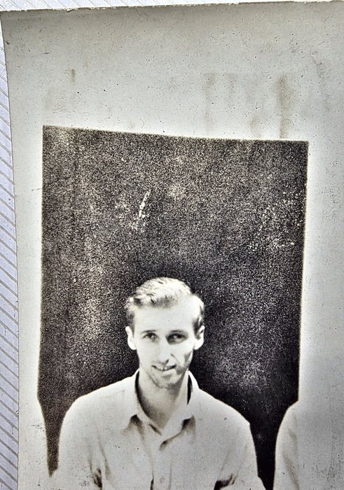 A young man in a light open-collar shirt, photographed head-and-shoulders against a dark wall, with another man's shoulder at the right edge of the frame. Named on the back as "Rod. Leonard" of Berkeley, California; the print carries a US Army censor stamp.
