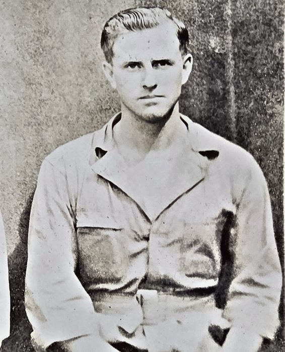 A young man with his hair combed back sits facing the camera in a light shirt with flap breast pockets, his hands in his lap and the shoulder of another man just visible at the left edge. The back reads "Glenn W. Snoo...", the surname running off the right edge of the frame -- Snow, Snook and Snodgrass are all possible -- with "Liberty, Kans" beneath it.