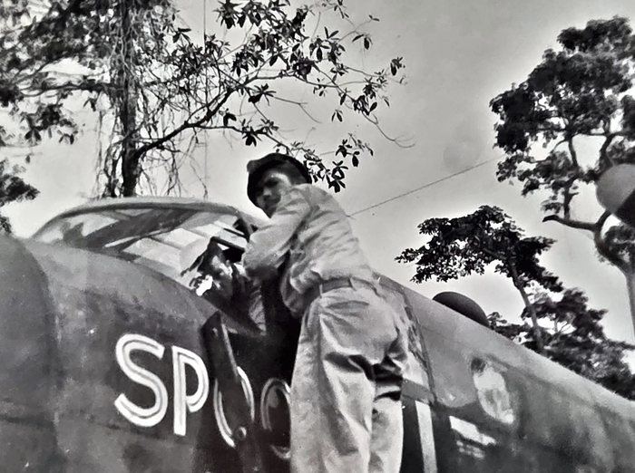 The same photograph again, re-shot so the back could be read. The nose carries the outlined, drop-shadowed capitals <b>SPO</b>, with the rest of the word behind the man's leg and the edge of the print. The back reads 