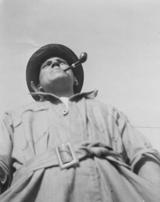 Allen smoking a pipe, looking up — a candid, lighter moment.
